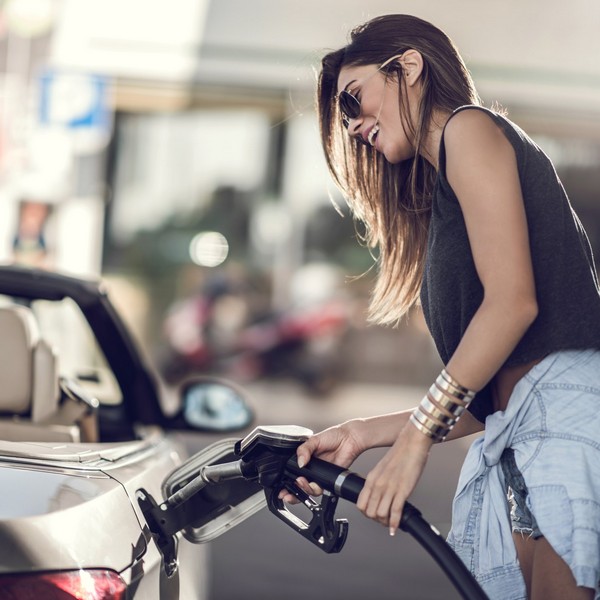 Beautiful woman refueling the gas tank at fuel pump.